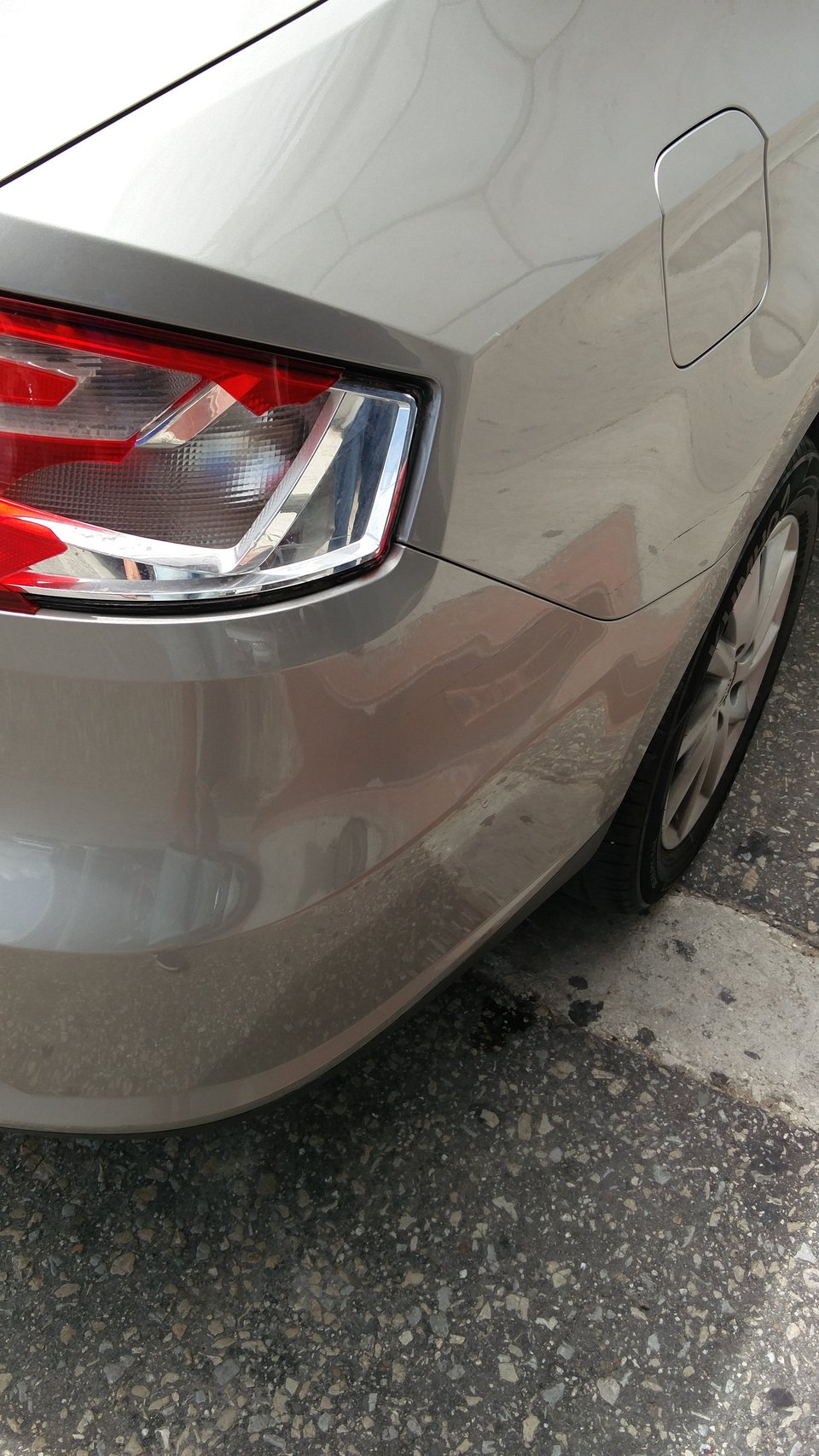 Szare wynajęte auto z uszkodzonym tylnym światłem.